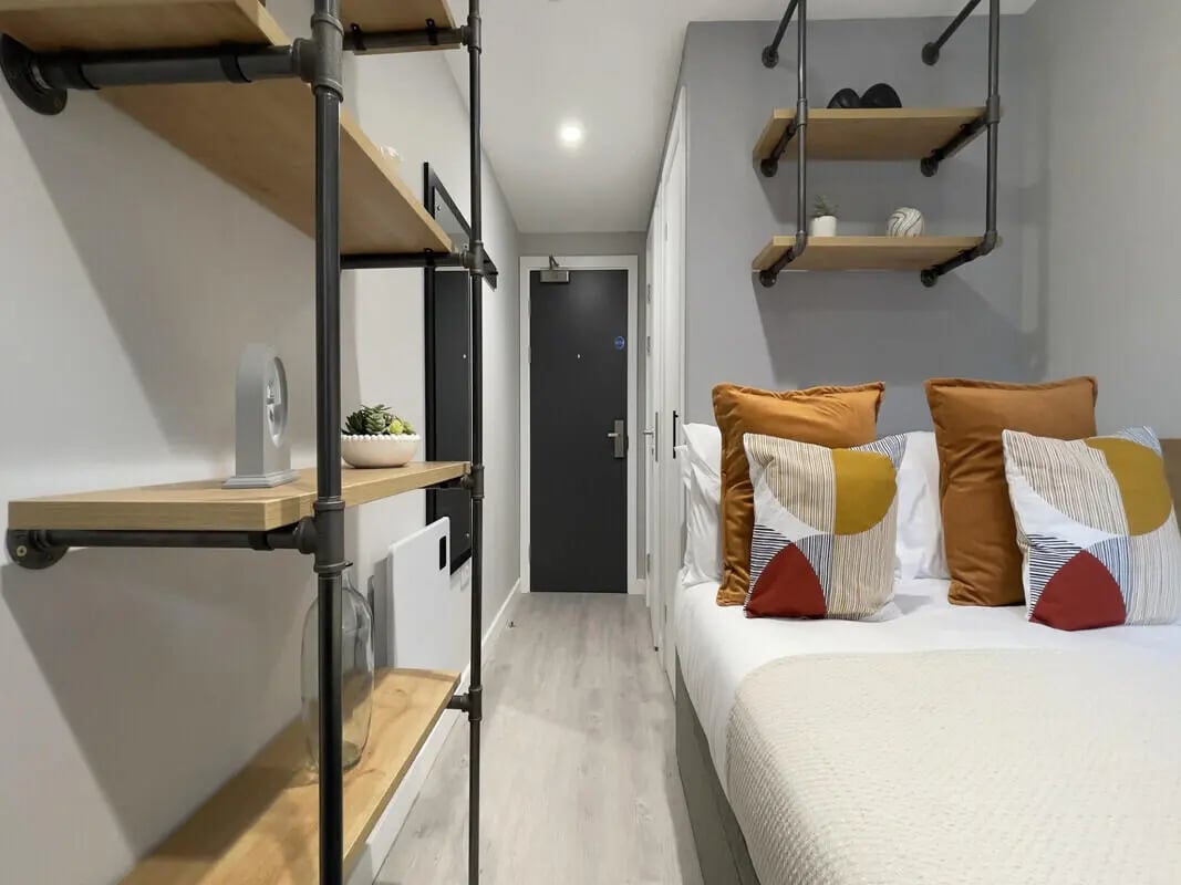 Bed with cushions shelves and door Bedroom at The Coal Yard in York Student Accommodation