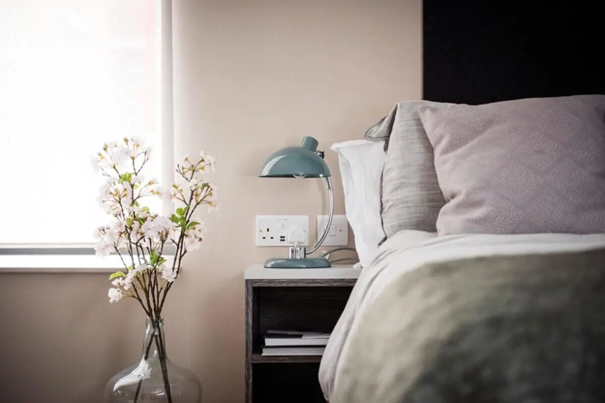 Bed pillows lamp vase and flowers bedroom at Collegiate Roman House in Derby Student Accommodation