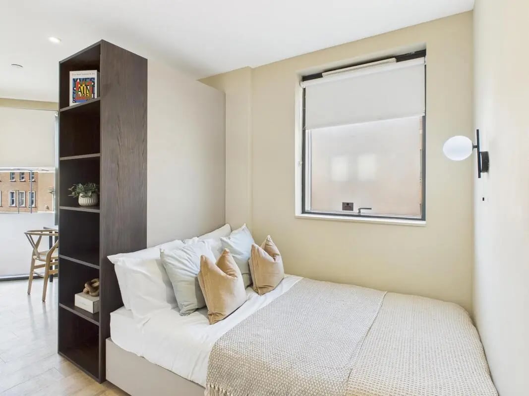 Bed with pillows shelves and window bedroom at Tribu Kingston in Kingston Upon Thames Student Accommodation