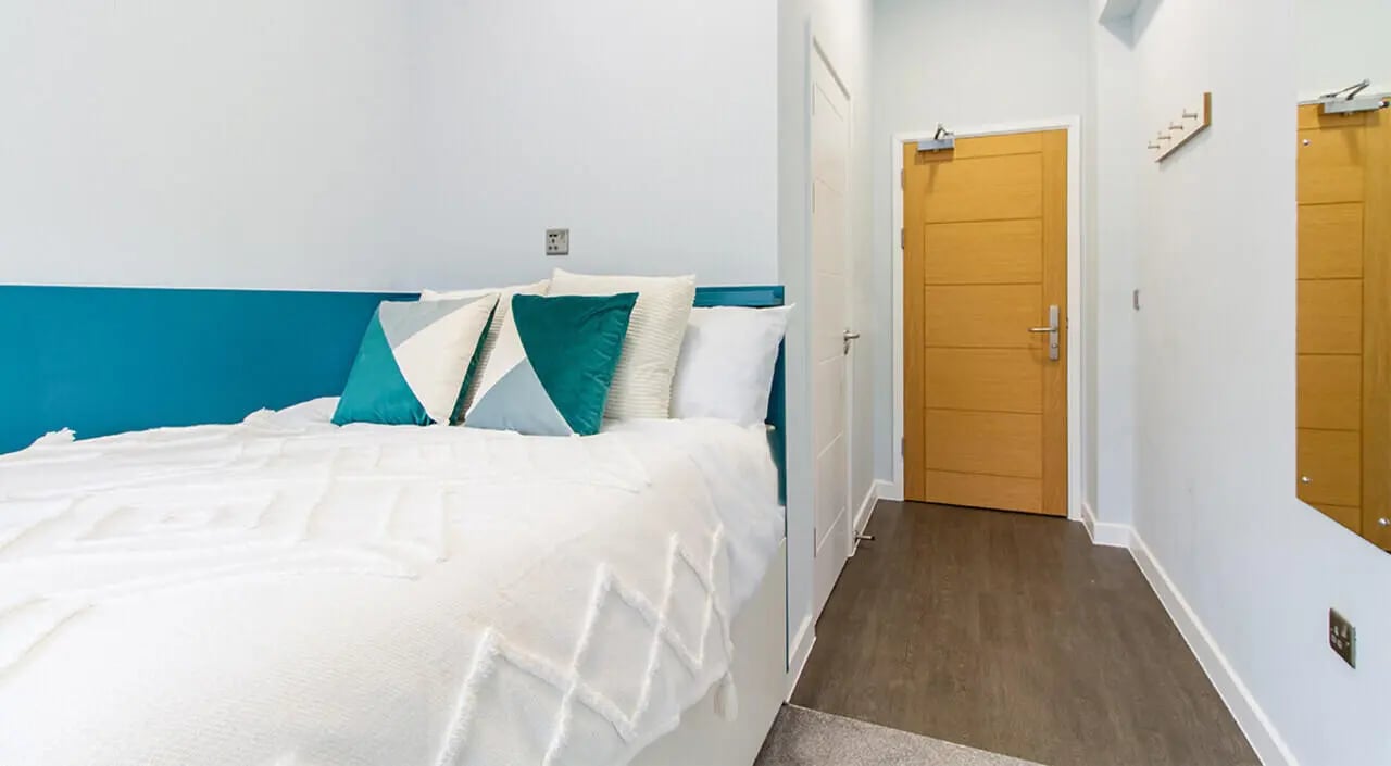 Bed with teal headboard pillows and doorway bedroom at Urban Student Village in Coventry Student Accommodation