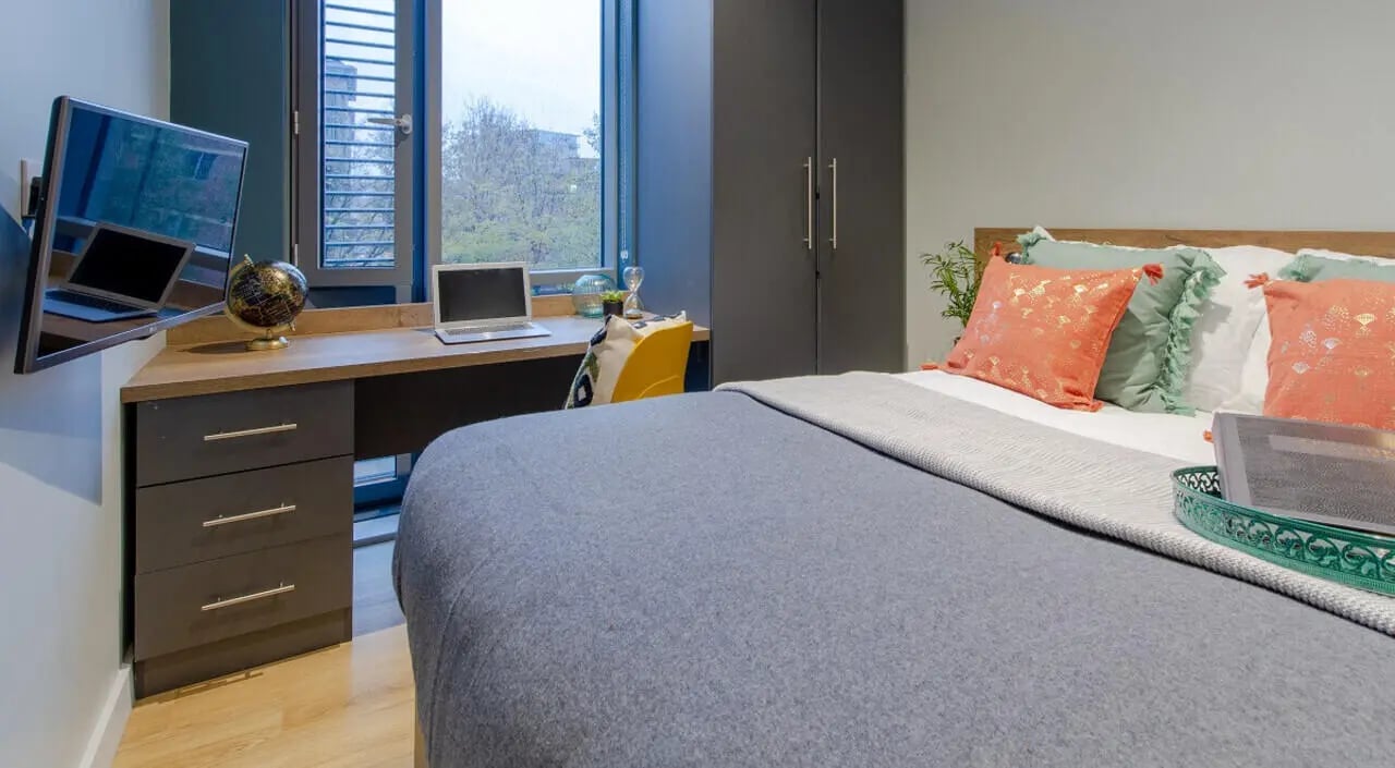 Bed with decorative pillows desk and TV bedroom at Crown House in Sheffield Student Accommodation