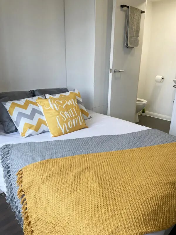 Bed with yellow and grey pillows and throws bedroom at Hockley Point in Nottingham Student Accommodation