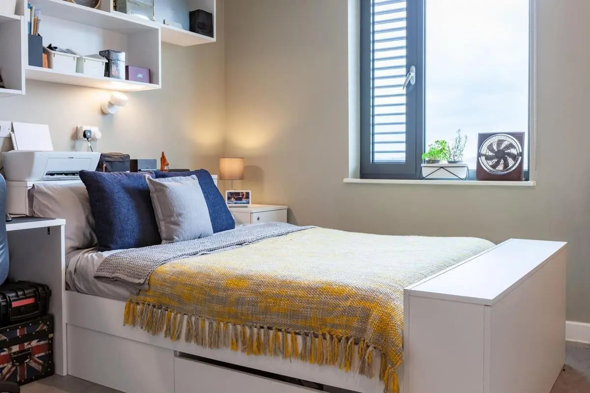 Bed with yellow blanket and pillows bedroom at Atlas House in Exeter Student Accommodation
