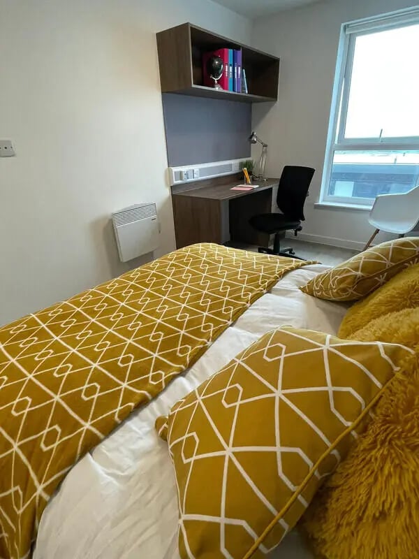 Bed with yellow patterned throw desk and chair bedroom at Phoenix Place in Liverpool Student Accommodation