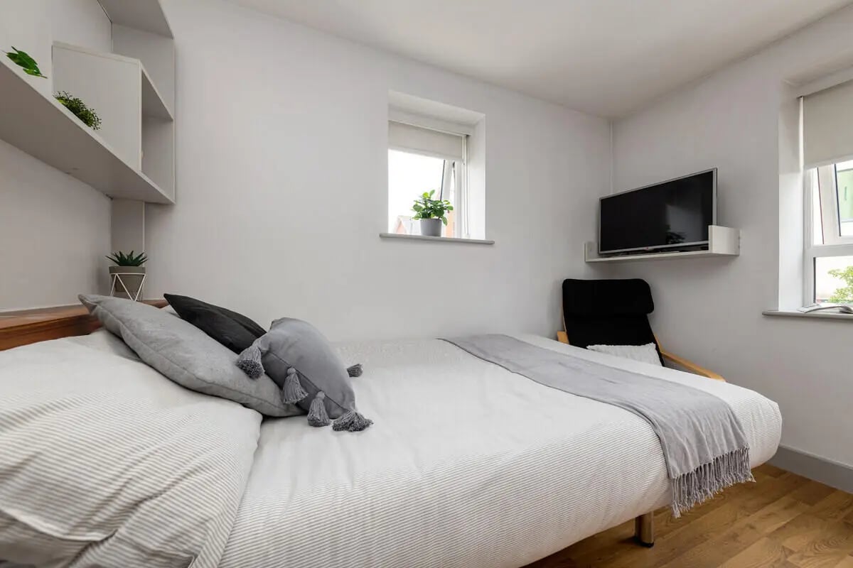 Bed with pillows TV chair and shelves bedroom at Collegiate St James Street in Portsmouth Student Accommodation