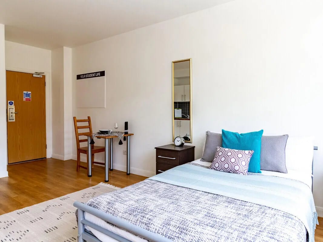 Bed with pillows table chair and door bedroom at Portobello Garrow House in London Student Accommodation