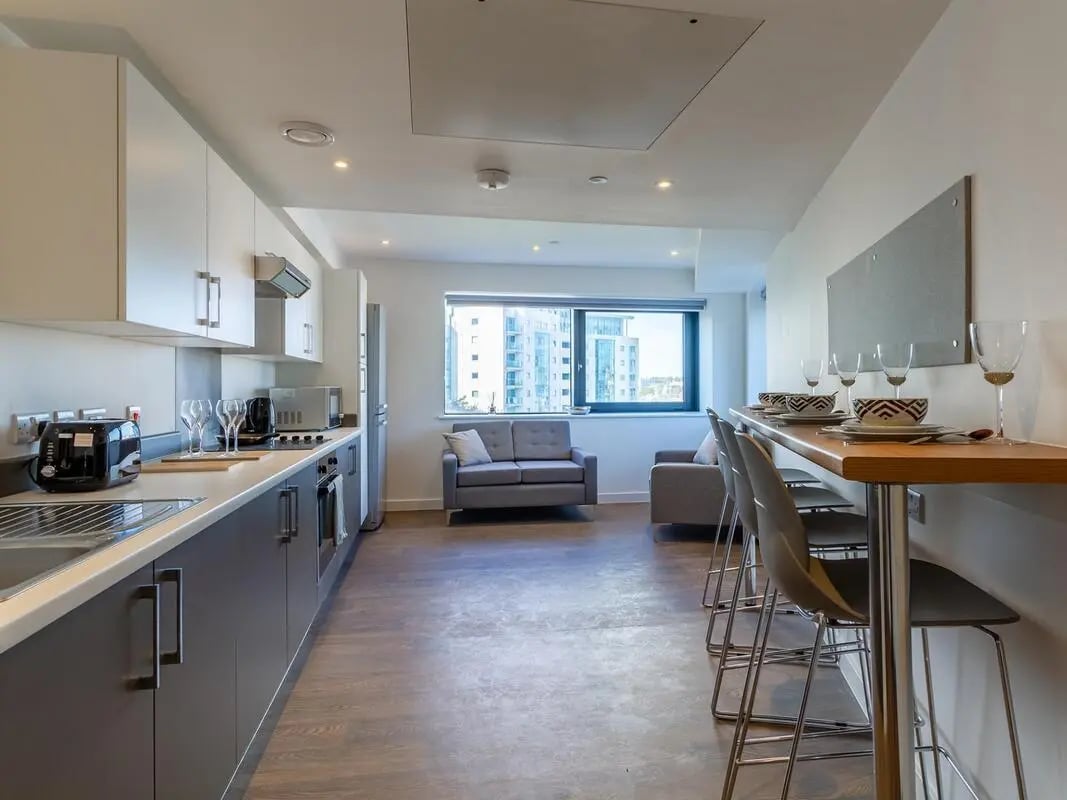 Kitchen with bar seating and living area at Saltwater Place in Plymouth Student Accommodation