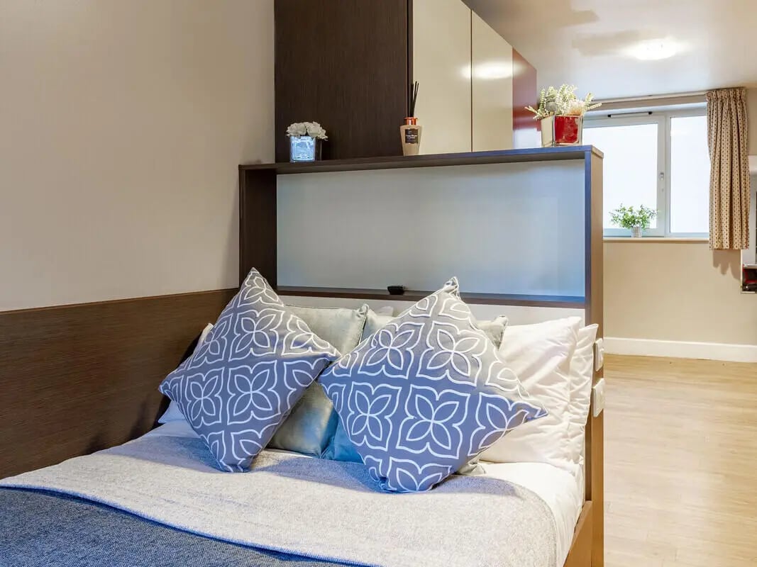 Bed with patterned pillows and duvet bedroom at Camden Hawley Crescent in London Student Accommodation