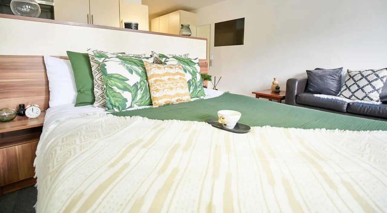 Bed with green and leaf pillows sofa bedroom at Windsor Court in Liverpool Student Accommodation