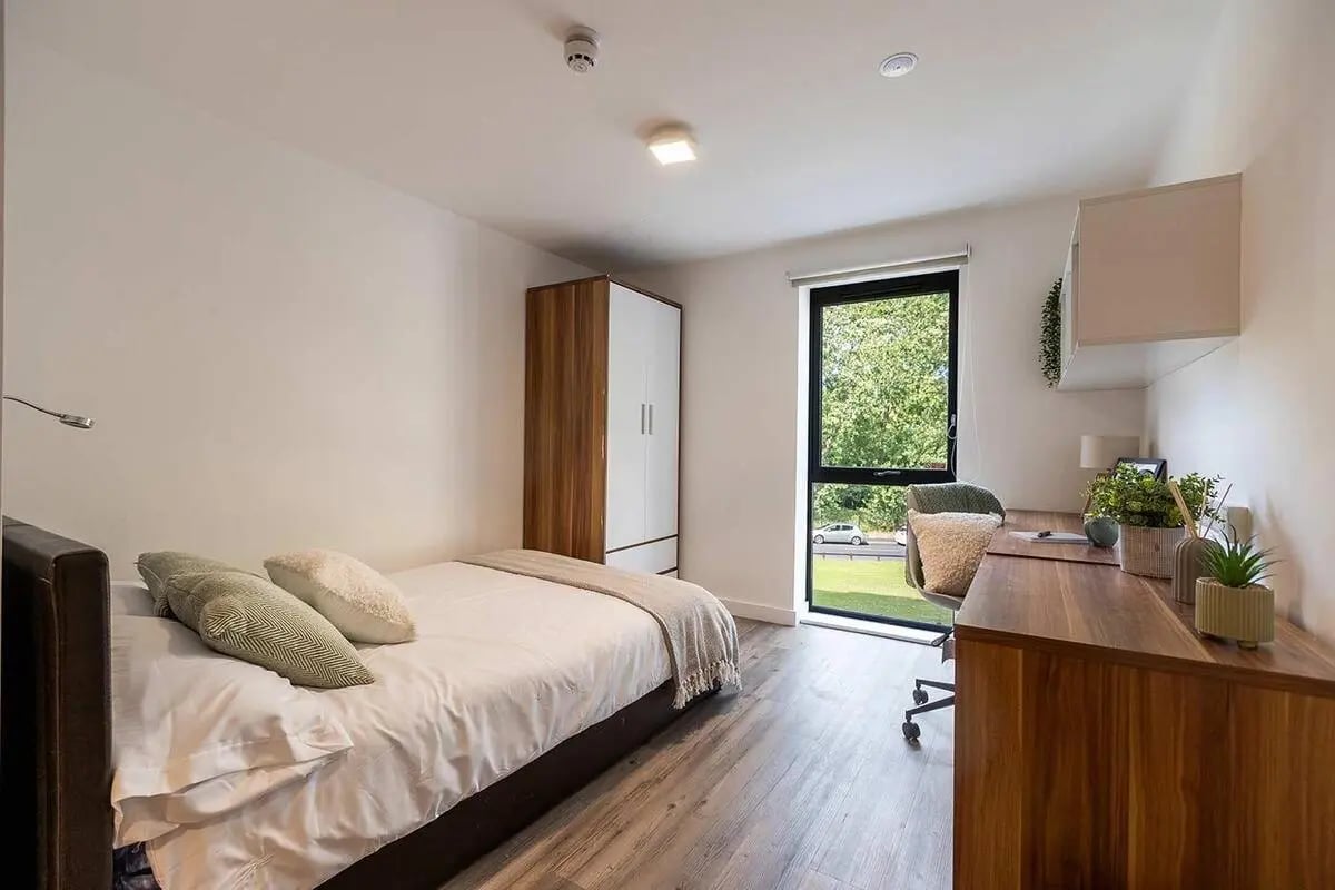 Bed wardrobe desk chair window and plants bedroom at Asquith House in Leeds Student Accommodation