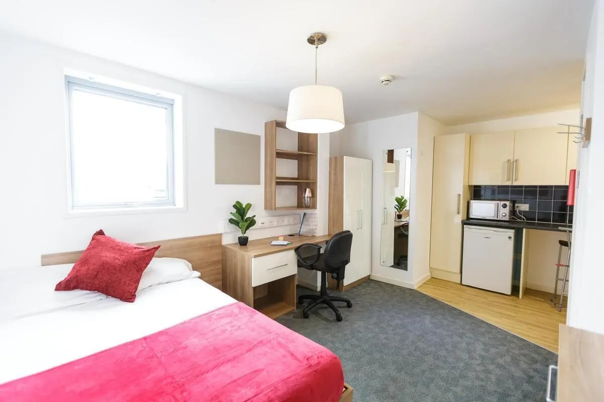 Bed desk mirrored wardrobe kitchen area living room at AXO Islington in London Student Accommodation