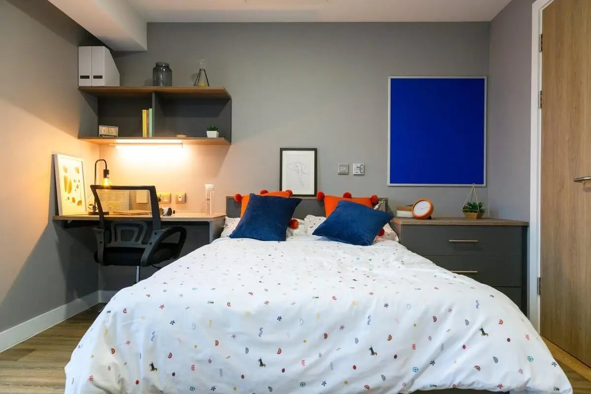 Bed desk chair shelves and blue noticeboard bedroom at Luneside in Lancaster Student Accommodation