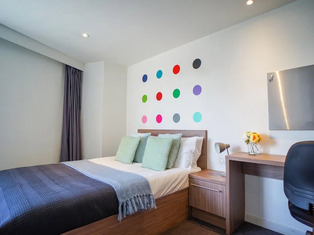 Bed with pillows curtains desk and chair bedroom at Gallery Apartments in Glasgow Student Accommodation