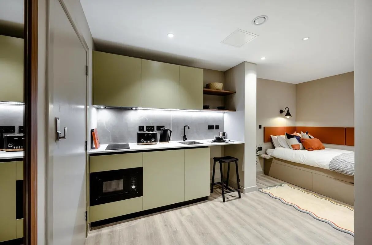 Kitchenette and bed with colorful pillows bedroom at The Pepper Mill in Edinburgh Student Accommodation