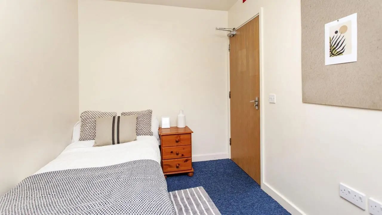 Bed with bedside table door artwork bedroom at Parham Student Village in Canterbury Student Accommodation