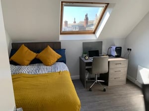 Bed desk with laptop alarm clock bedroom at Welton Road in Leeds Student Accommodation