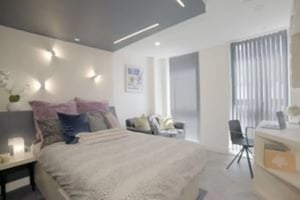 Bed with pillows couch desk chair and blinds bedroom at The Orchard in Leicester Student Accommodation