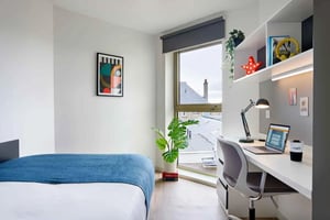 Bed desk plant framed art and bookshelf bedroom at Edinburgh Gorgie in Edinburgh Student Accommodation