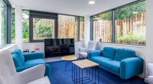Blue sofas grey chairs television with garden view living room at Goods Corner in Edinburgh Student Accommodation
