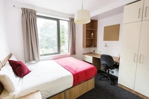 Bed with red blanket bedside tables large window Bedroom at AXO Camden in London Student Accommodation