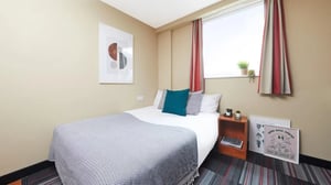 Bed with teal pillows and art bedroom at Market Way in Coventry Student Accommodation