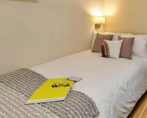 Bed with laptop glasses phone and pillows Bedroom at The Hub in London Student Accommodation