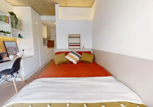 Bed with orange bedding and desk area bedroom at iQ Flinders House in London Student Accommodation