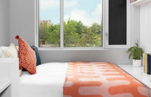 Bed with orange blanket and pillows bedroom at Scape Canada Water in London Student Accommodation