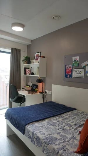 Desk chair bed with blue blanket bedroom at Theatre House in Coventry Student Accommodation