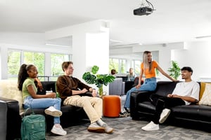 Four students relaxing on black sofas living room at Liberty Park in Leicester Student Accommodation