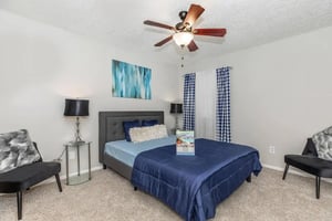 Bed chairs lamp ceiling fan artwork bedroom at Villas De La Plaza in Austin Student Accommodation