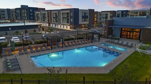 Pool with lounge chairs and modern apartment buildings exterior at Claro at High Point in Aurora Student Accommodation