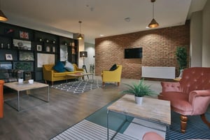 Yellow sofas armchairs shelves with decor living room at Bath Street in Glasgow Student Accommodation