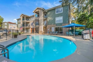Apartment building with pool lounge chairs and grill exterior at The Landing at Appleyard in Tallahassee Student Accommodation