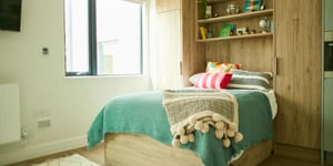 Bed with teal throw and decorative pillows bedroom at Canvas Student - Quintana Gate in Exeter Student Accommodation