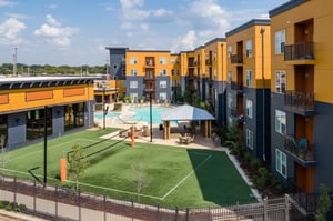 Modern apartment complex with pool and volleyball court exterior at The Quarters at Stillwater in Stillwater Student Accommodation