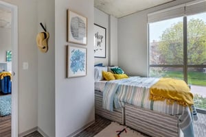 Bed with striped bedding and yellow throw bedroom at Rise At Riverfront Crossings in Iowa City Student Accommodation