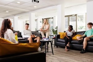 Students relax on couches in lounge area at Sir Charles Groves Hall in Manchester Student Accommodation