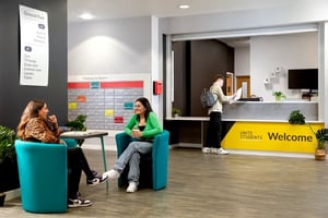 Two students sit in chairs by postboxes reception area at Orion Point in Southampton Student Accommodation