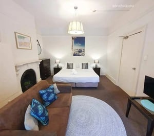 Sofa bed chest of drawers bedside lamps sleeping area at ume 152 Darlinghurst Village in Sydney Student Accommodation