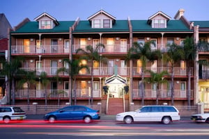 Brick building with balconies palm trees and cars exterior at ume Redfern Village in Sydney Student Accommodation