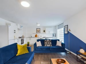 Blue sofas kitchen area and coffee table living room at 6 Bedroom House at 2, Flat 2, Windsor House, Clint Road West in Liverpool Student Accommodation