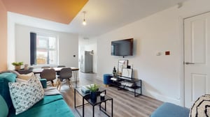 Teal sofa dining table and television living room at 6 Bedroom House at 18, Halsbury Road in Liverpool Student Accommodation