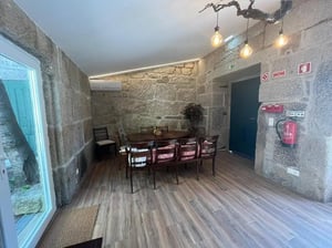 Wooden dining table with chairs and stone walls dining area at Spacious Double Bedroom ensuite close to Barragem de Vascoveiro in Guarda Student Accommodation