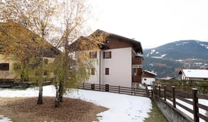 Building with balconies snow scattered grass trees exterior at Homely and modern 1-bedroom apartment in Molina in Valdidentro Student Accommodation