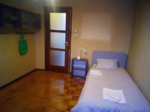 Bed, nightstand, door, and shelf bedroom at Very cosy single bedroom near the João de Deus metro in Vila Nova De Gaia Student Accommodation