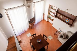 Dining table sofa bookshelves television living room at Bright loft studio in well-connected location in Castellammare o Loggia in Palermo Student Accommodation