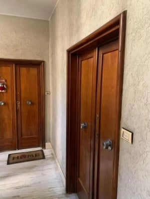 Wooden doors with knobs and doormat hallway exterior at Large double bedroom close to the Trastevere train station in Rome Student Accommodation