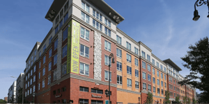Modern building with NOW OPEN banner exterior at College and Crown Apartments in New Haven Student Accommodation