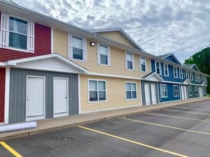 Colorful townhouses with parking lot exterior at Campus Communities - College Town Apartments in Big Rapids Student Accommodation
